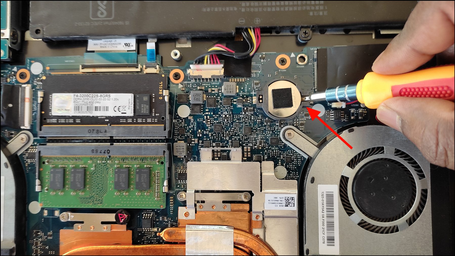 Motherboard CMOS coin-cell battery being removed to reset BIOS settings